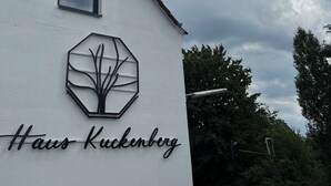 A building with a white exterior, a hexagonal logo with a tree design, and the text "Haus Kuckenberg" on the side. - Haus Kuckenberg (Burscheid)