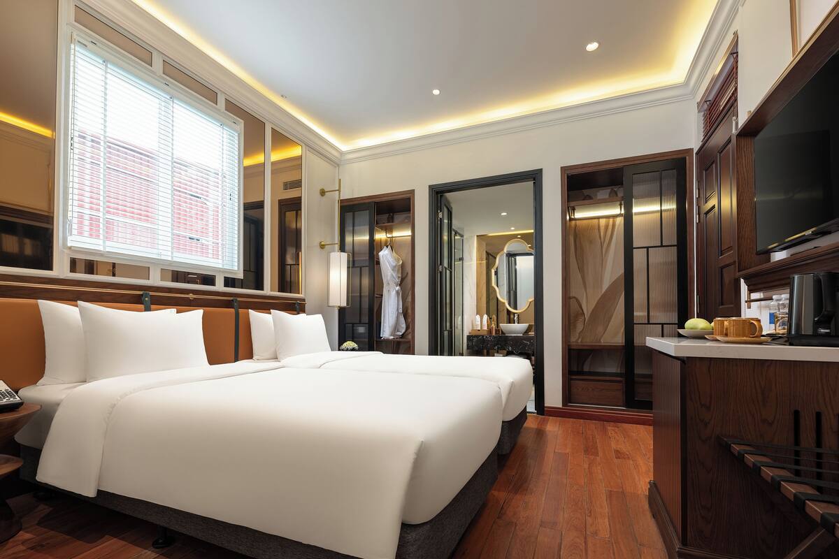 A hotel room with a large bed, a vanity with a mirror, and a kitchenette.