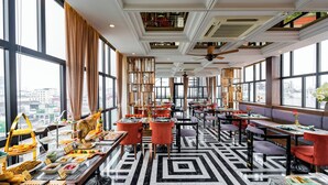 Ein modernes Restaurant mit hohen Decken, großen Fenstern und einem geometrisch gemusterten Boden.