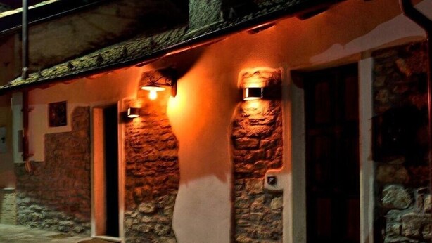 A stone building with a rustic exterior and two illuminated wall sconces. - Il Borgo del Castello Large Double Room Tulip (Cremolino)