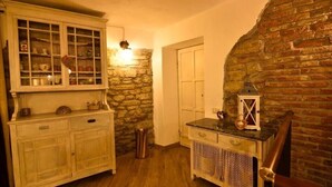 A rustic room with a stone wall, wooden cabinets, and a small table with a lantern. - Il Borgo del Castello Large Double Room Tulip (Cremolino)
