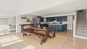 Une cuisine moderne avec des meubles de couleur bleu foncé, un réfrigérateur en acier inoxydable et un îlot central doté de tabourets de bar.