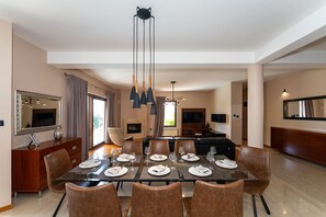 A modern dining area with a glass table, brown leather chairs, and pendant lighting.
