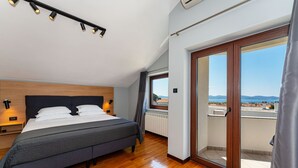 Un dormitorio con cama, lámparas de noche, una ventana con vistas y una puerta corrediza de vidrio a un balcón.
