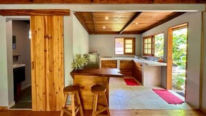 Une cuisine compacte avec des meubles en bois, un îlot central et deux tabourets.
