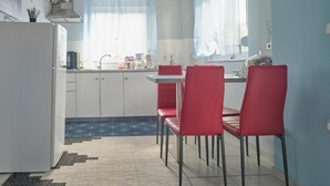 Una cocina funcional con armarios blancos, una mesa de comedor roja y sillas a juego.