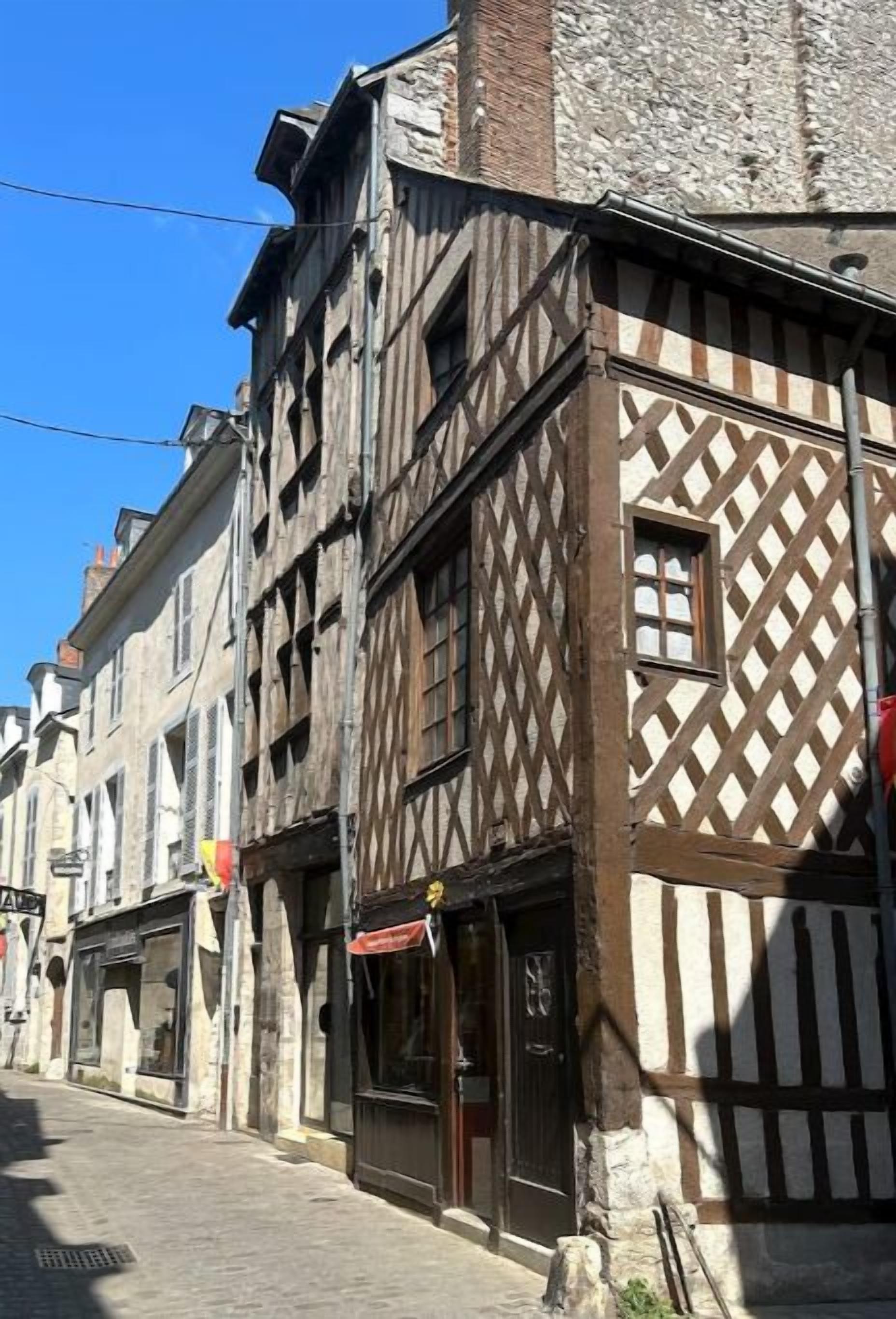 Une rue étroite bordée de bâtiments à colombages, dont la construction combine des éléments en pierre et en bois.