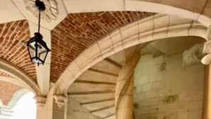 Un escalier en colimaçon dans un bâtiment aux murs de pierre et au sol carrelé.