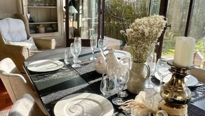 Un coin repas avec une table dressée pour six personnes, un vase décoratif et une bougie.