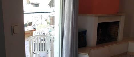 A living room with a fireplace, a sliding glass door to a patio, and a small table.