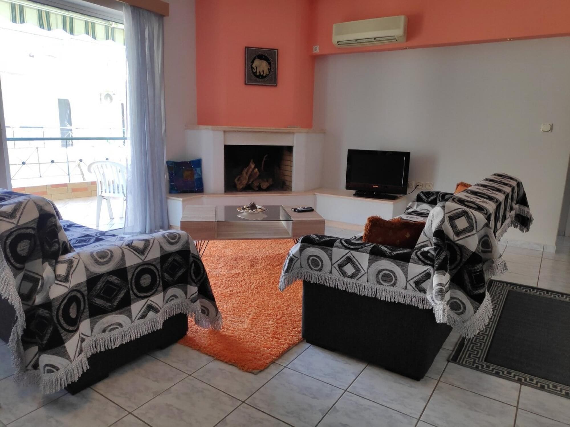 Un salon avec une cheminée, un téléviseur et un ensemble de meubles (canapé, fauteuils, etc.).