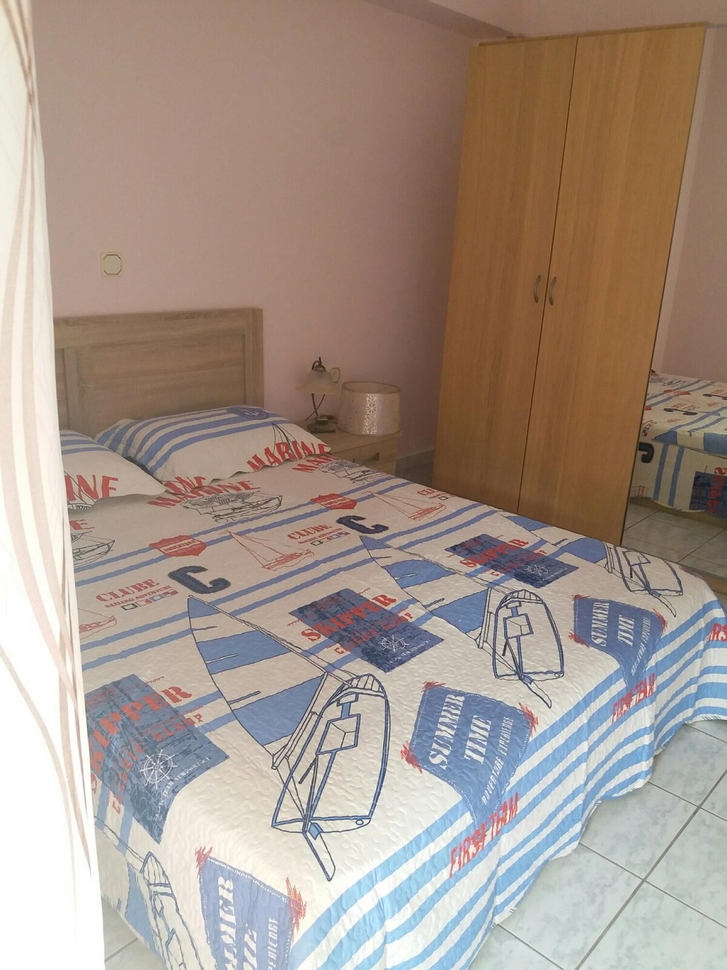 Un dormitorio con una cama, un armario de madera y una mesita de noche con lámpara.