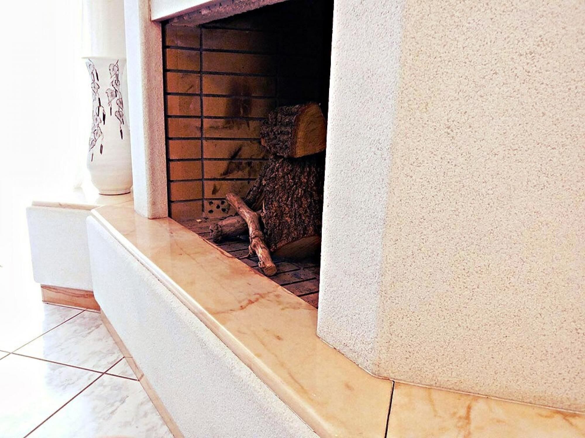 Une cheminée avec un foyer orné de carreaux et des bûches à l’intérieur.