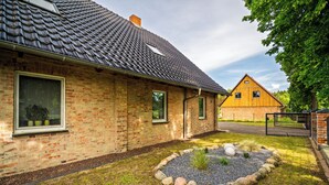 A brick house with a tiled roof, a gravel garden, and a wooden fence. - Ferienhaus Nationalparkidylle in Boek (Rechlin)
