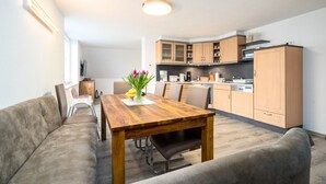 A modern kitchen with wooden cabinets, a dining table, and a sofa. - Ferienhaus Nationalparkidylle in Boek (Rechlin)