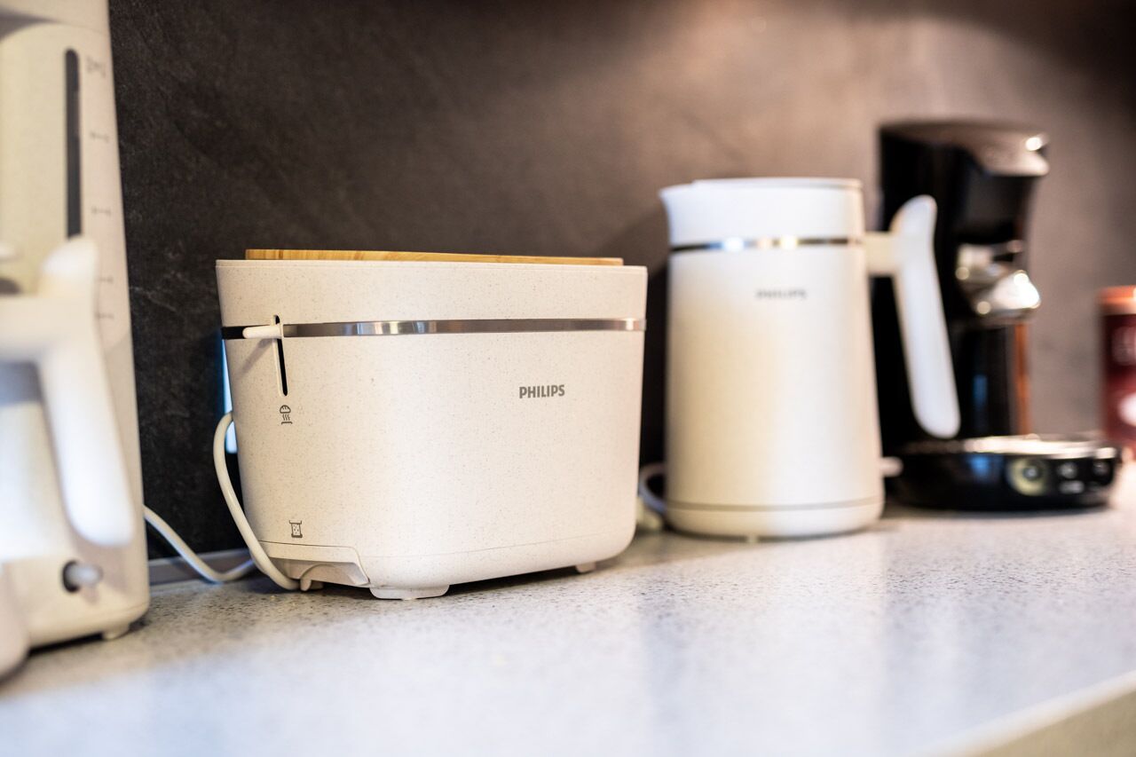 Une cuisine équipée d’une machine à café Philips, d’une cafetière blanche et d’un appareil électroménager blanc, qui pourrait être un robot culinaire ou un mixeur.