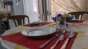 A dining table set with plates, cutlery, and a glass with a flower decoration. - Central Apartment in Agios Konstantinos (Kamena Vourla)
