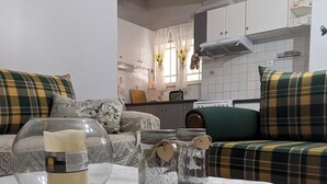A living room with a sofa set, a table with decorative jars, and a kitchen in the background. - Central Apartment in Agios Konstantinos (Kamena Vourla)