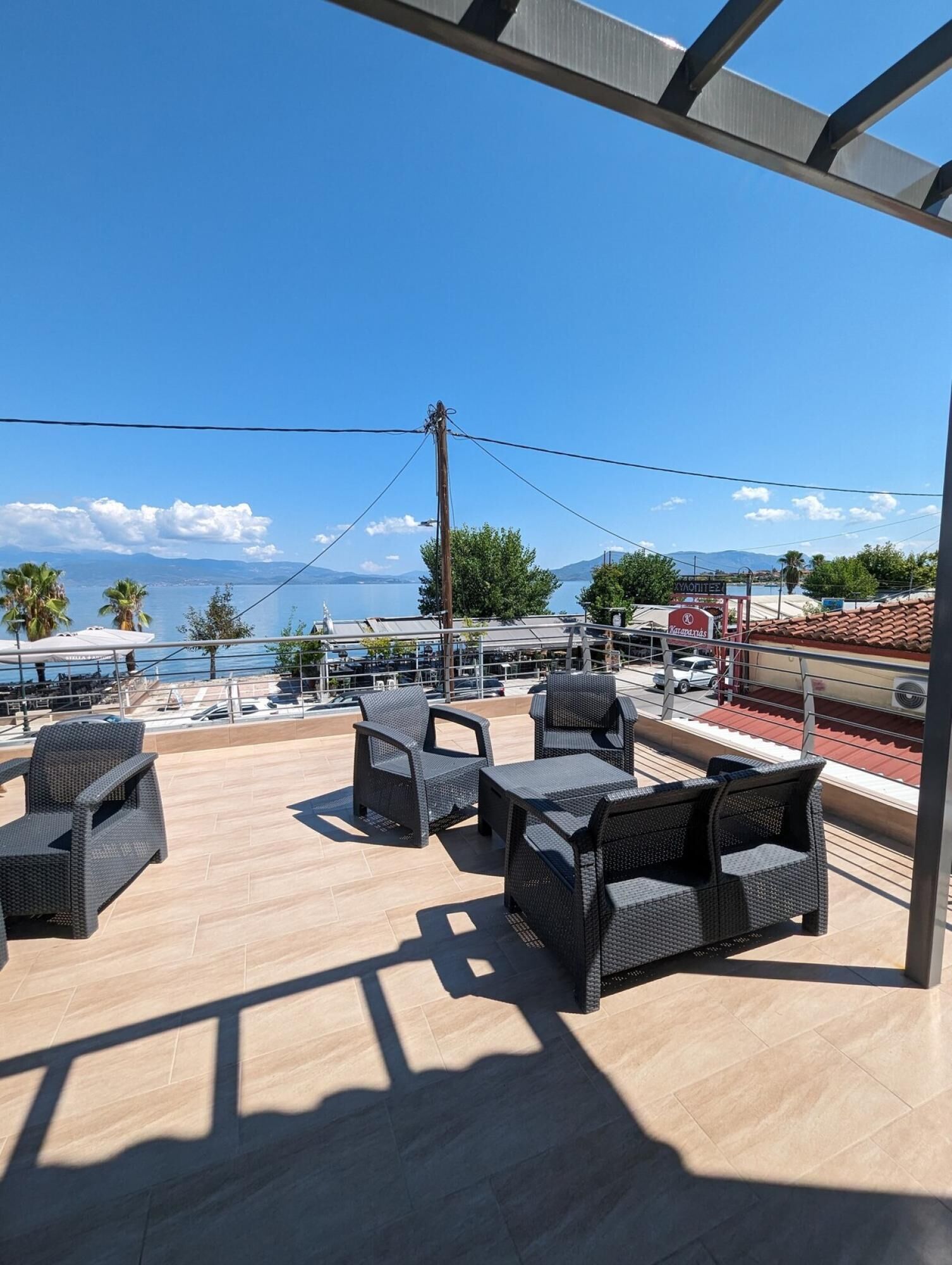 A terrace with wicker furniture and a view of the sea and mountains.