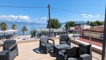 A terrace with wicker furniture and a view of the sea and mountains.