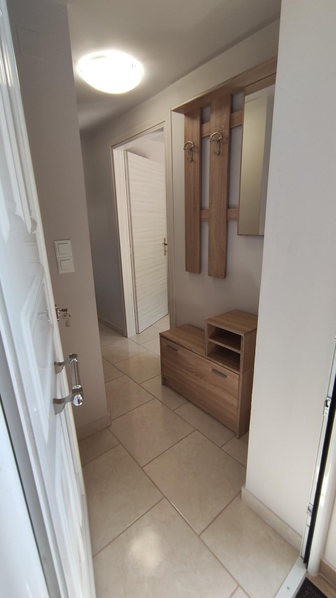 A hallway with a wooden vanity, a mirror, and a door leading to another room.