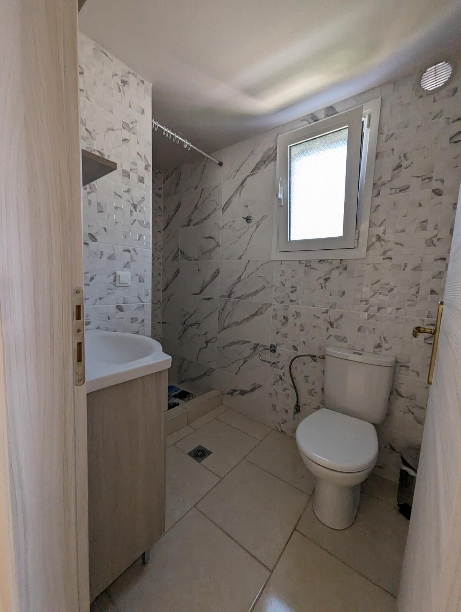 A bathroom with a marble-patterned wall, a white sink, and a toilet.