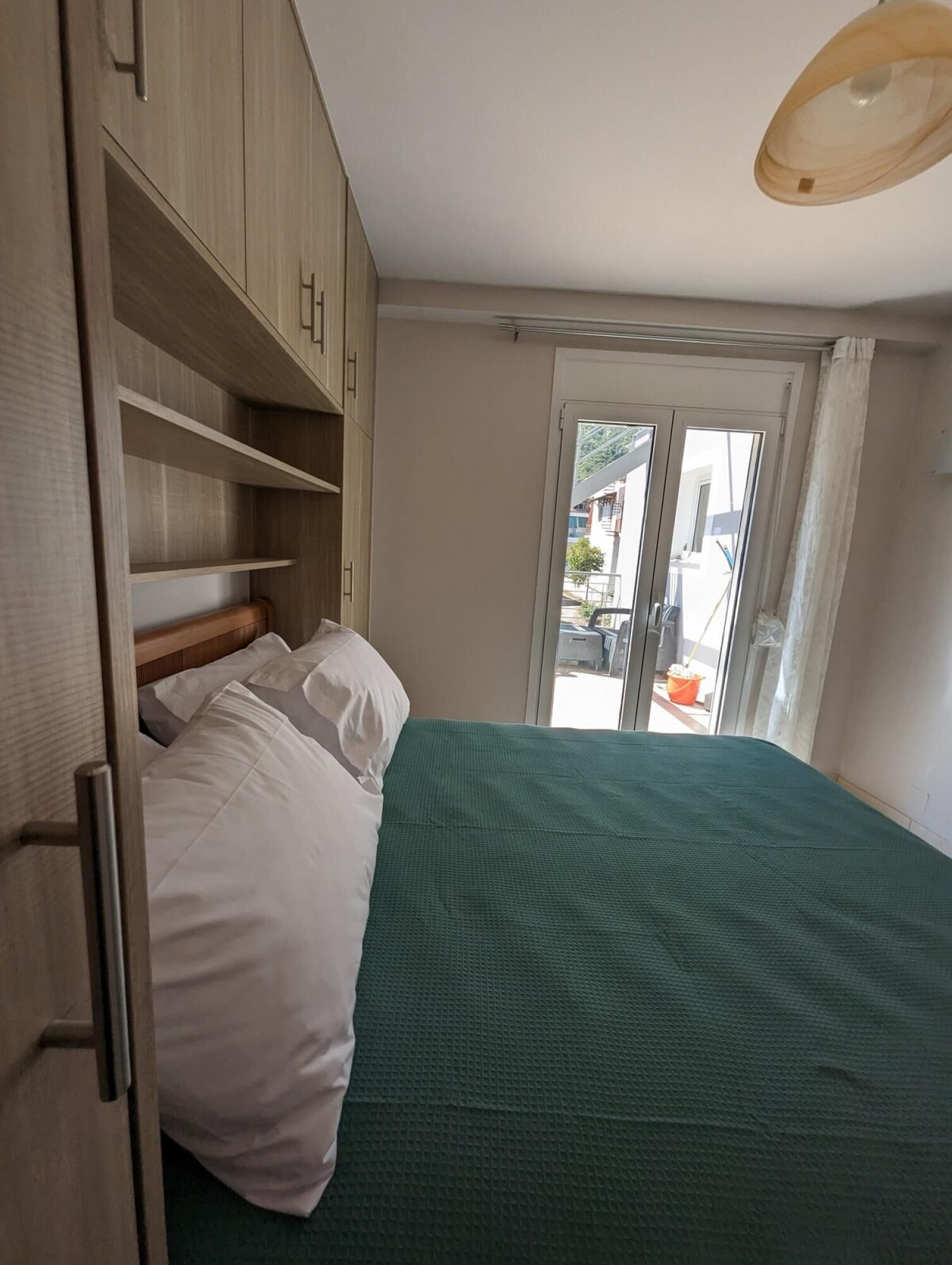 Une chambre à coucher avec un lit, une armoire en bois et une fenêtre donnant sur la rue.