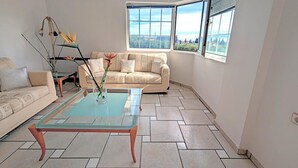 Un salón con mesa de centro de vidrio, sofá color beige y vistas amplias por un gran ventanal.