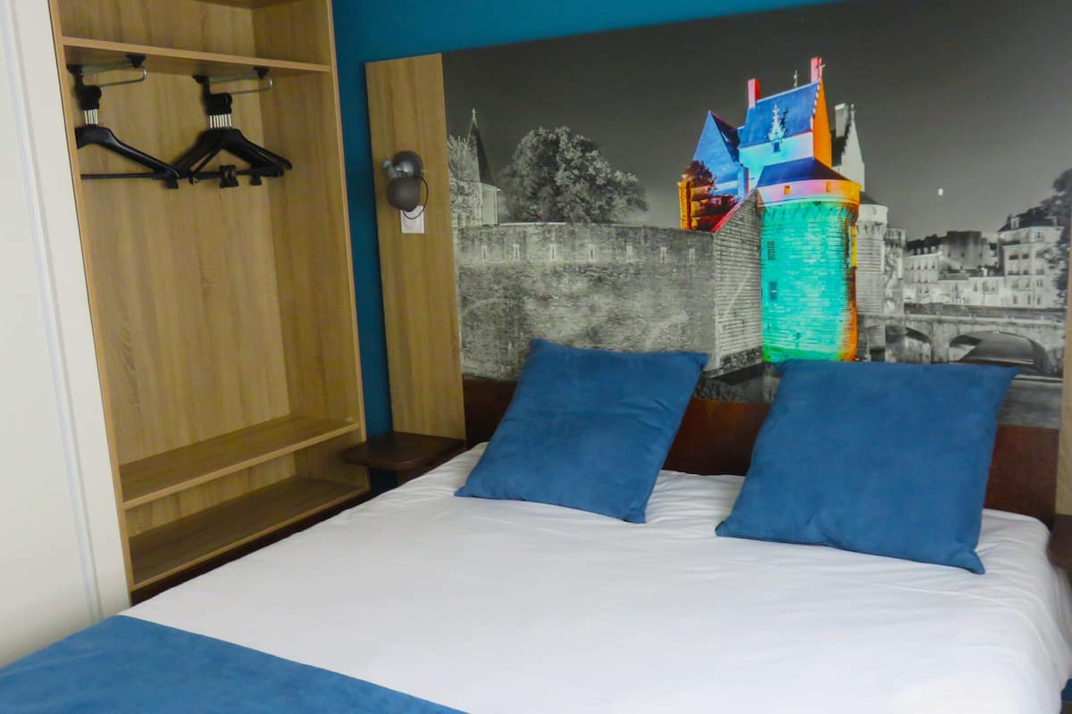 Ein Schlafzimmer mit einem Bett, zwei Kissen, einem Holzschrank und einer Wandmalerei.