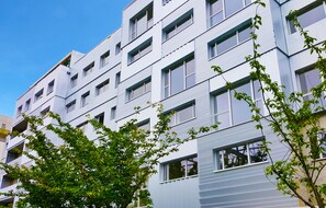 En byggnad med flera våningar, utformad i en modern arkitektonisk stil, med en rad fönster och balkonger.