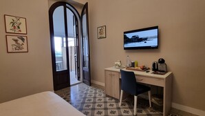 A hotel room with a bed, a desk with a chair, a television, and a window with a view of the outside. - B&B Arcovito 36 (Reggio Calabria)