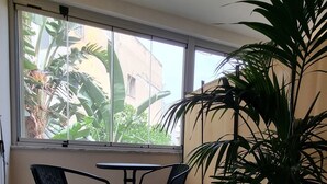 A room with a large window, two chairs, a table, and a potted plant. - B&B Arcovito 36 (Reggio Calabria)