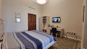 Ein Schlafzimmer mit Bett, Schreibtisch, Stuhl, Fernseher und Kleiderschrank.