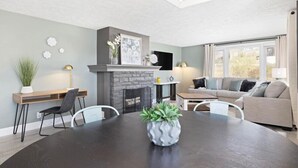 A modern living room with a fireplace, a dining table, and a sofa.