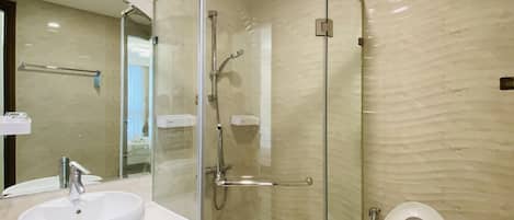 A modern bathroom with a glass-enclosed shower, a white sink, and a toilet.