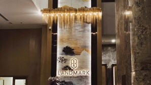 Un mostrador de recepción con un cartel vertical que muestra 'LANDMARK' y una pintura con un paisaje.