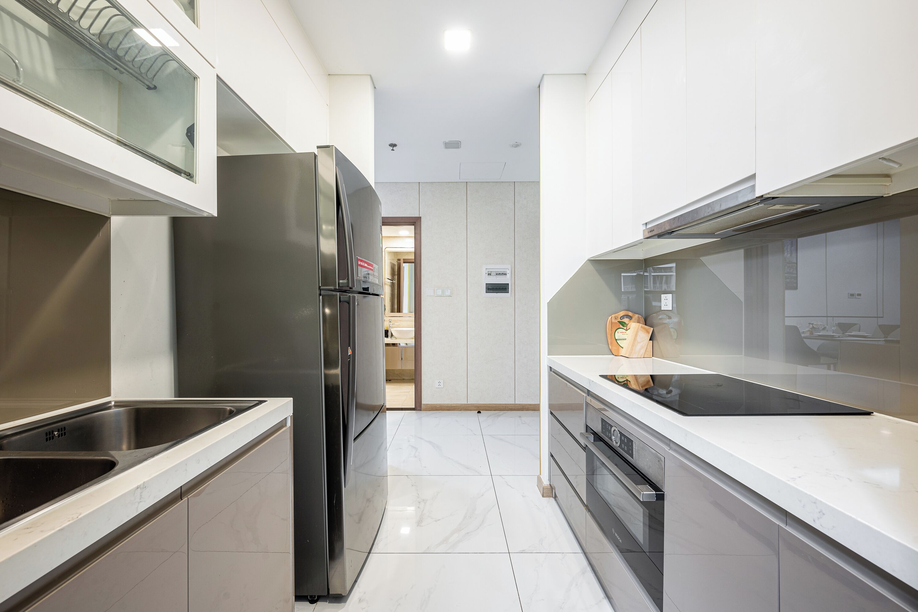 A modern kitchen with stainless steel appliances, white cabinetry, and a clean, tiled floor.