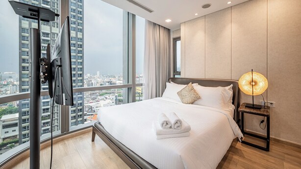 Una habitación de hotel moderna con una cama grande, vistas a la ciudad y un televisor montado en la pared.
