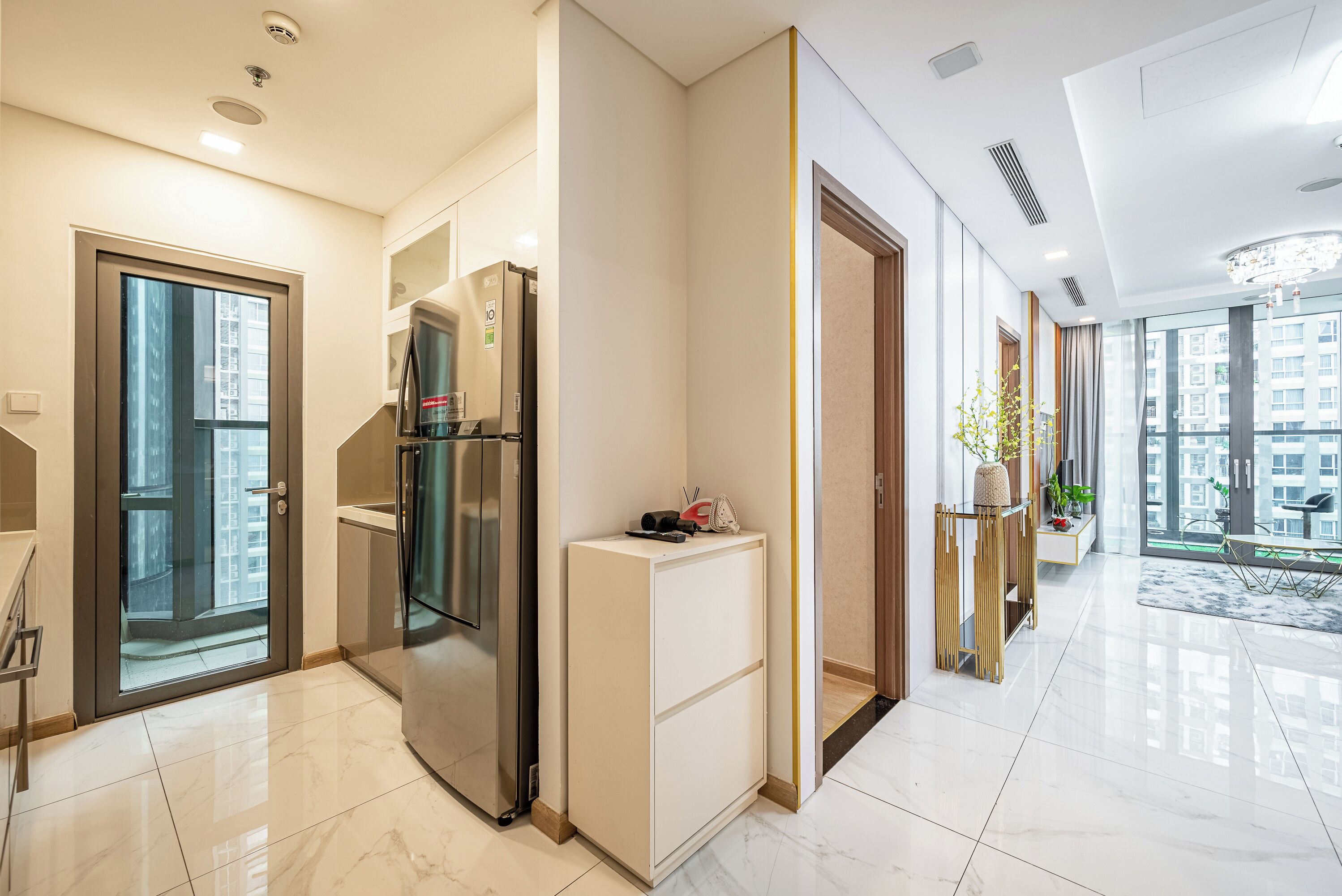 A modern kitchen with a built-in refrigerator, a small island, and a view of the city through large windows.