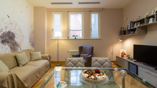 Ein modernes Wohnzimmer mit einer Couch, einem Glastisch, einem Sessel und einem Fernseher.