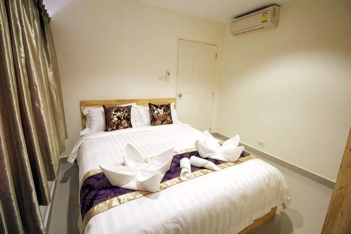 A hotel room with a bed, pillows, a blanket, and a towel.