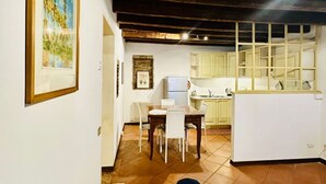 A compact kitchen with white cabinets, a dining table with chairs, and a window with a view of the outdoors. - San Pancrazio Home - Treviso (Treviso)