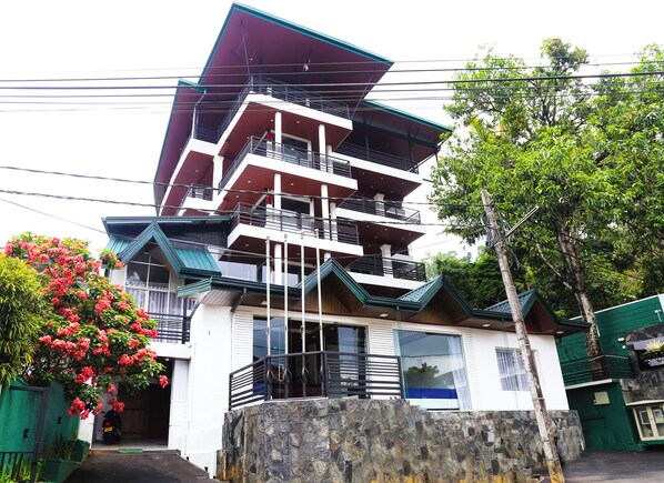 Stunning building with balconies and large windows, surrounded by lush greenery and a beautiful garden.