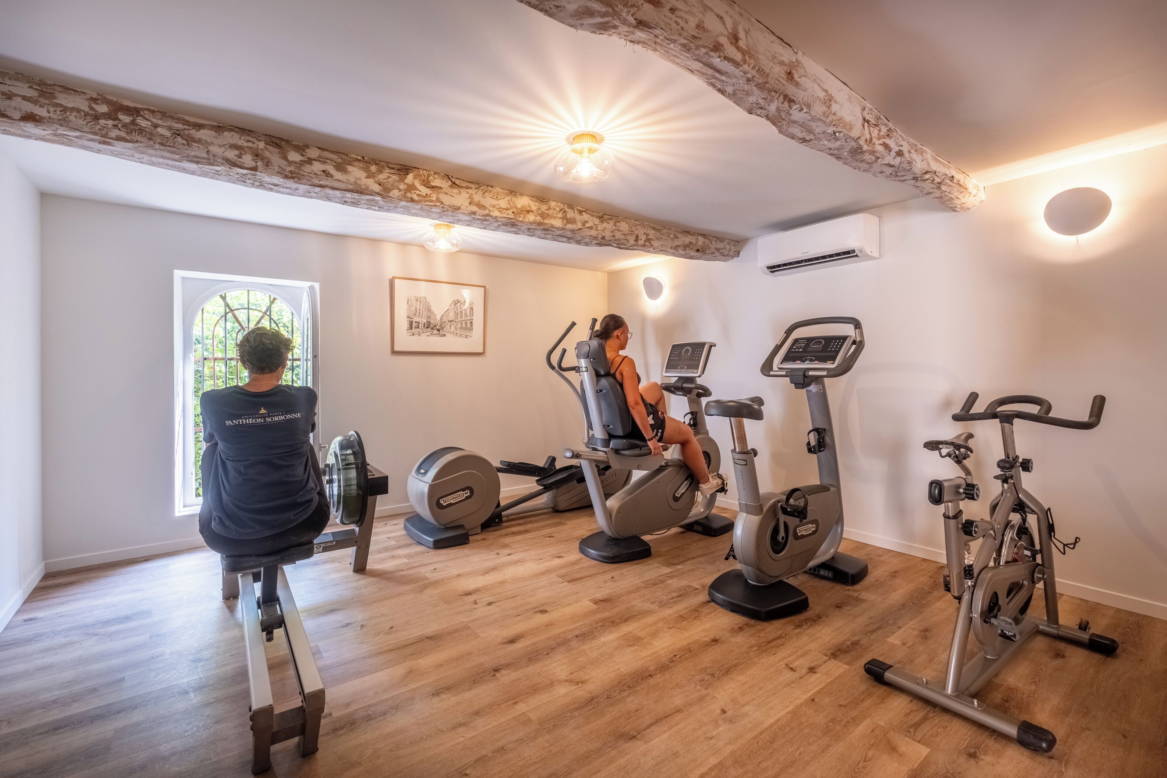 Un gimnasio en casa con diversos equipos de ejercicio, incluyendo una máquina de remo, una elíptica y una bicicleta estática.