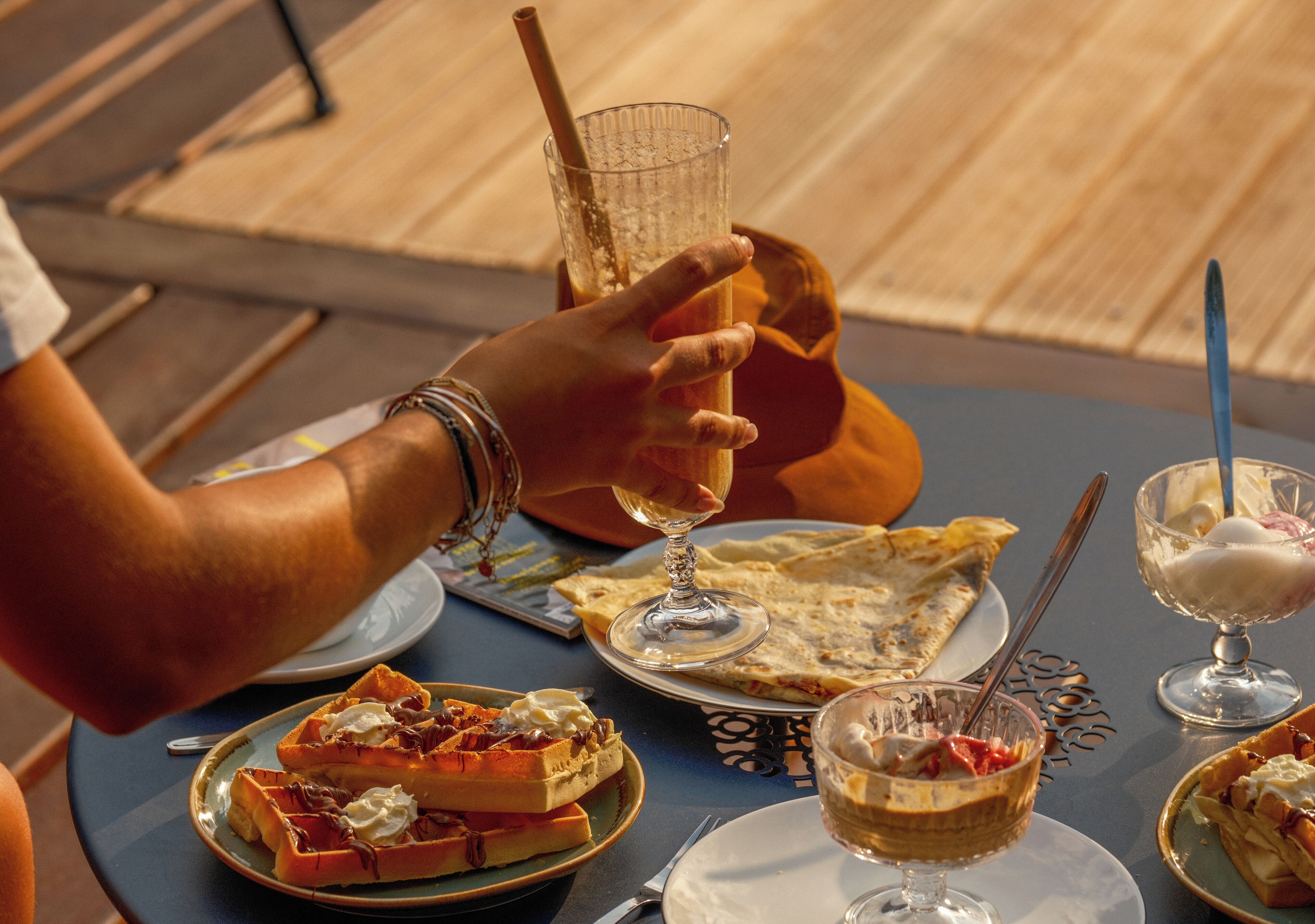 A table with waffles, a glass of wine, and a dessert.
