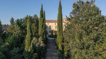 A stone staircase leading to a building with a red-tiled roof, surrounded by tall cypress trees.