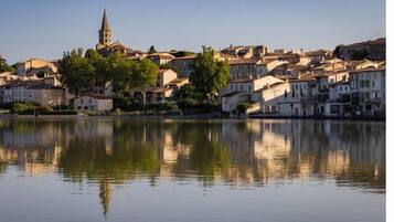 Une ville située au bord de l’eau, dotée de bâtiments historiques et d’un clocher d’église imposant.