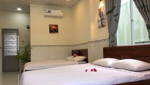 A hotel room with two single beds, a wooden headboard, a wall-mounted air conditioner, and a window with curtains. - Sunny Homestay Quy Nhon (Quy Nhon Nam)