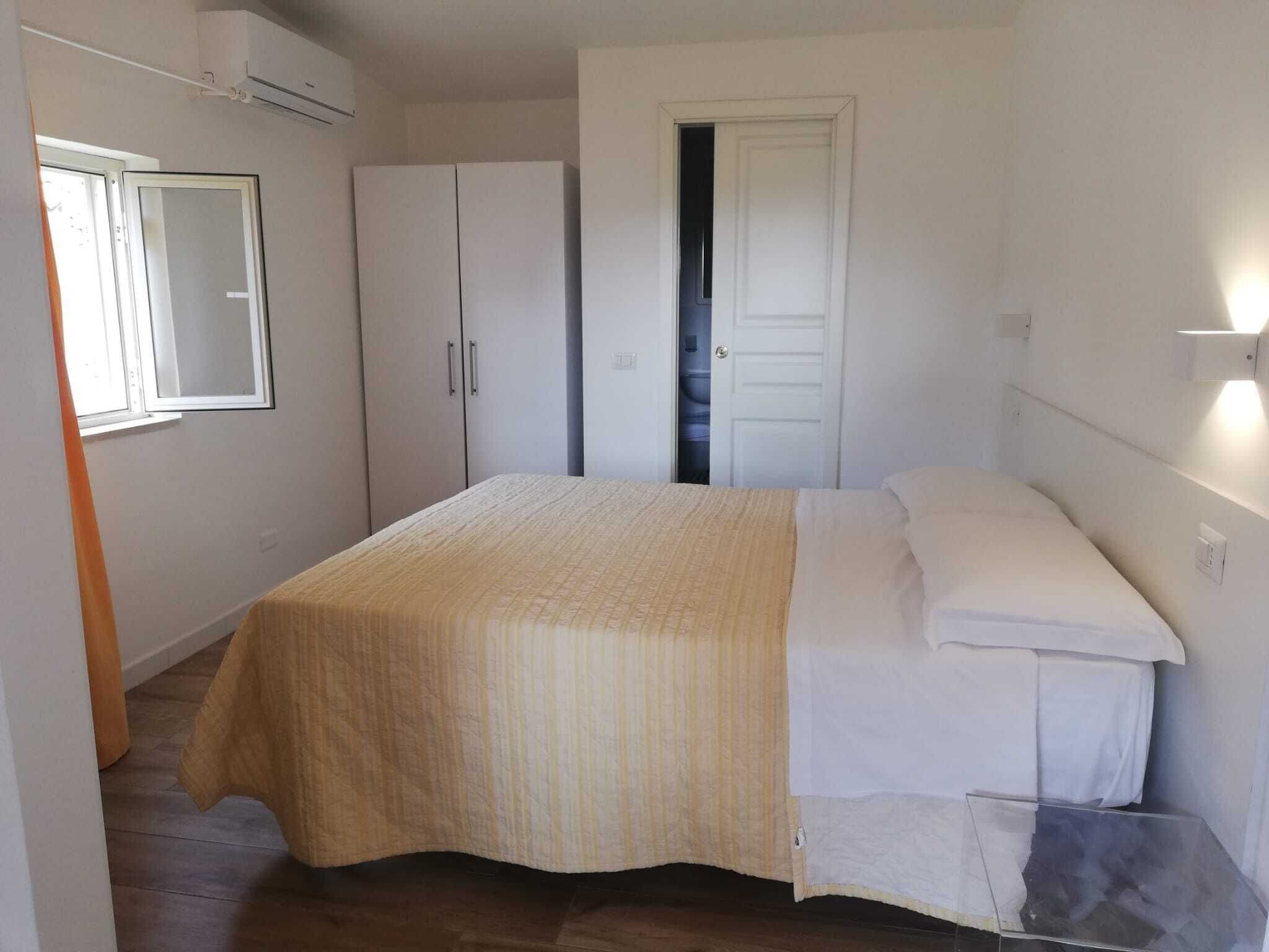 Una camera da letto con un letto, un armadio, uno specchio e una porta.