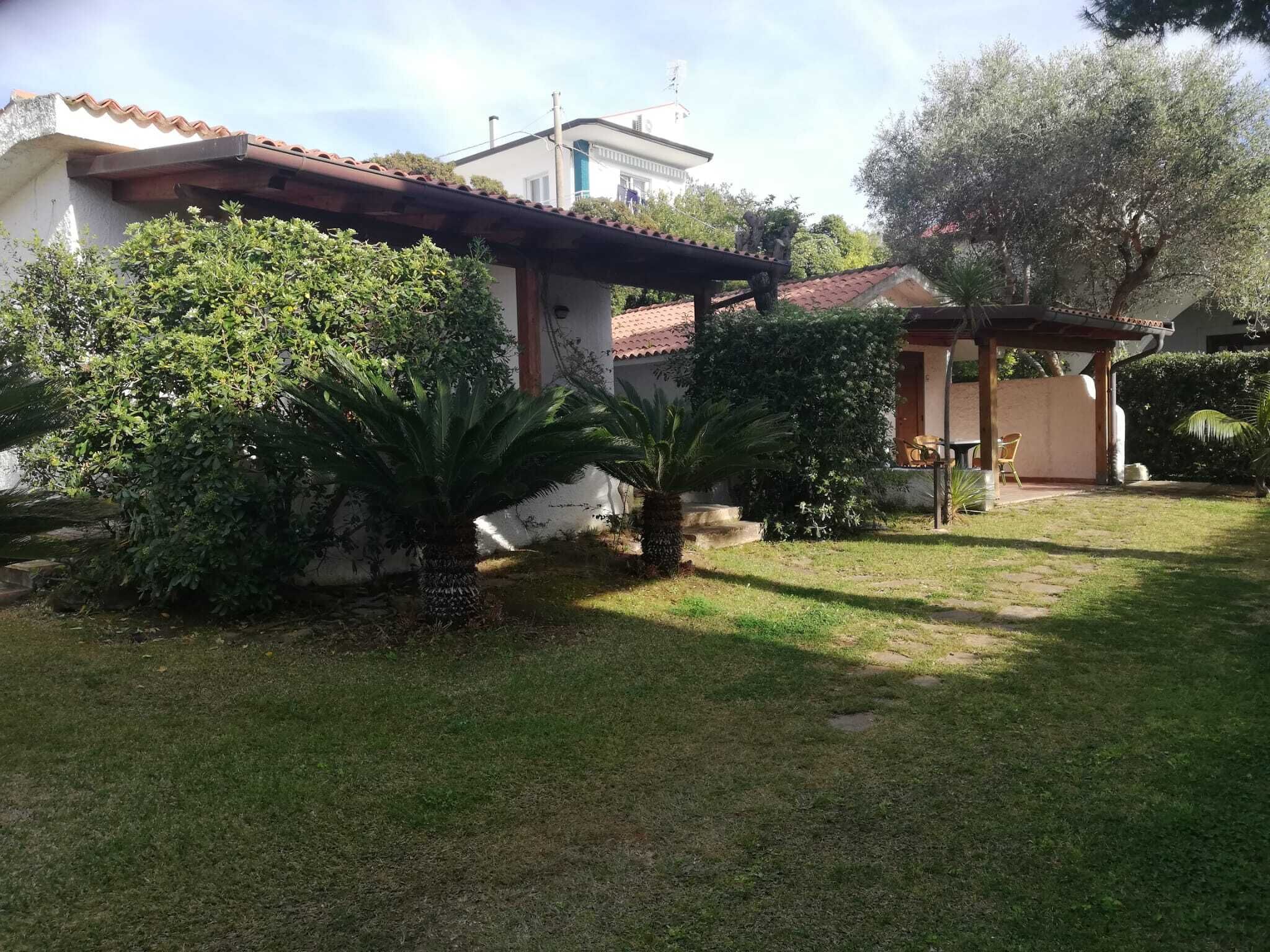 A house with a garden, a pergola, and a small patio area.
